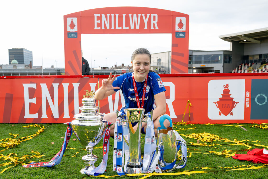 Cardiff City's Megan Bowen poses alongside the Bute Energy Welsh Cup, the Genero Adran Premier and the Genero Adran Trophy.